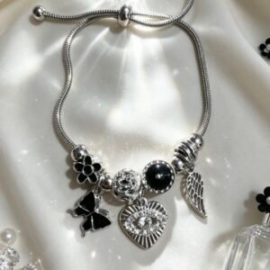 PULSERA PLATEADA CON DIJES DE CORAZON CON OJO MALVADO Y ALA DE ANGEL MARIPOSA NEGRA GGL-0001