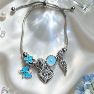 PULSERA PLATEADA CON DIJES DE CORAZON CON OJO MALVADO Y ALA DE ANGEL MARIPOSA AZUL GGL-0001